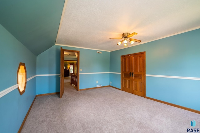 unfurnished bedroom featuring ceiling fan, carpet floors, a textured ceiling, and vaulted ceiling