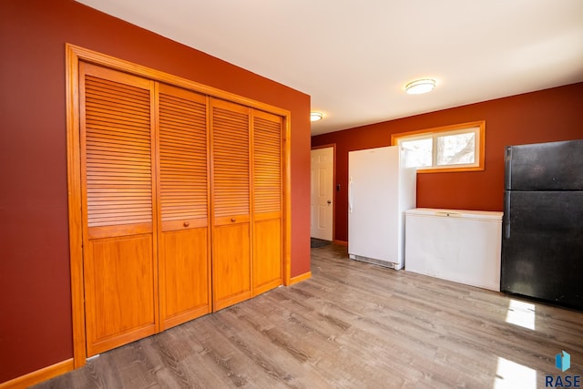 interior space featuring light wood-type flooring, black fridge, and a closet