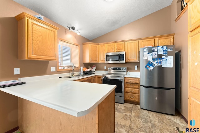 kitchen with kitchen peninsula, appliances with stainless steel finishes, a textured ceiling, vaulted ceiling, and sink