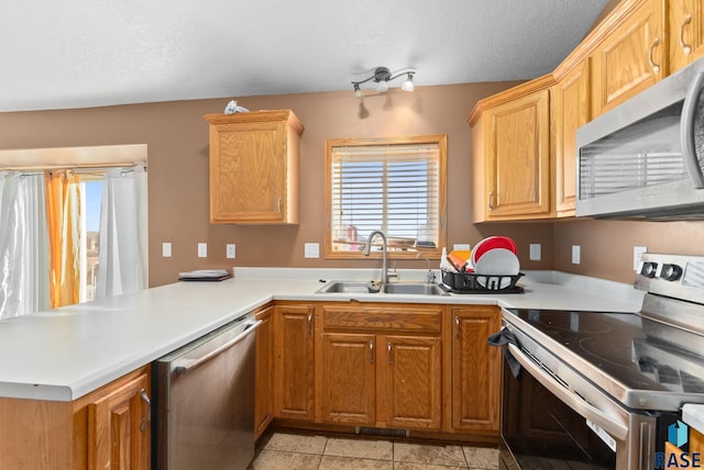 kitchen with sink, a textured ceiling, appliances with stainless steel finishes, light tile patterned flooring, and kitchen peninsula