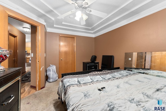 carpeted bedroom with a tray ceiling, ceiling fan, and ornamental molding