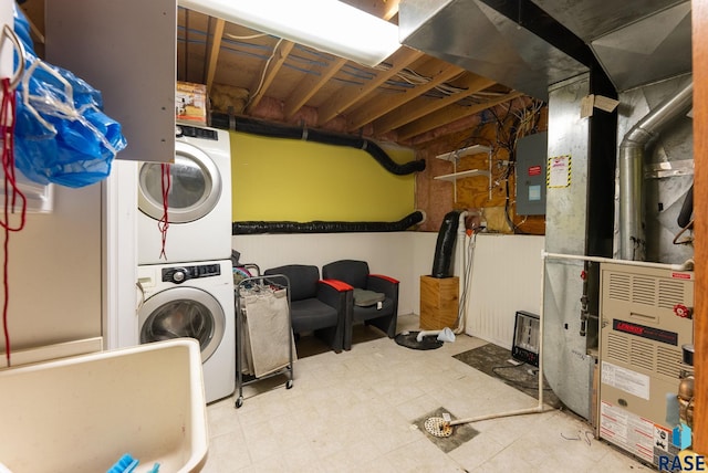 laundry area featuring heating unit and stacked washer and clothes dryer