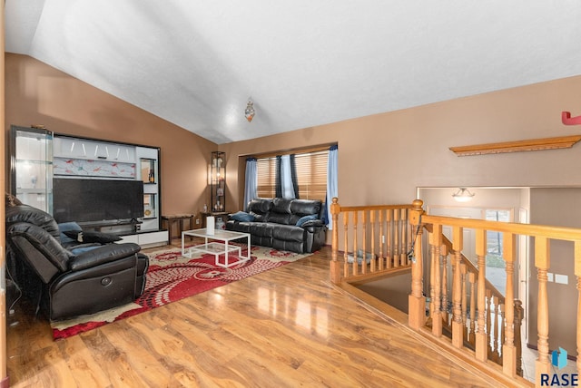 living room featuring a wealth of natural light, wood-type flooring, and vaulted ceiling