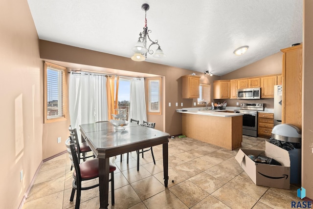 kitchen with light brown cabinets, vaulted ceiling, appliances with stainless steel finishes, decorative light fixtures, and kitchen peninsula