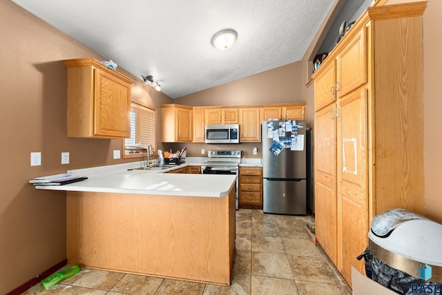 kitchen with kitchen peninsula, stainless steel appliances, vaulted ceiling, sink, and light brown cabinets