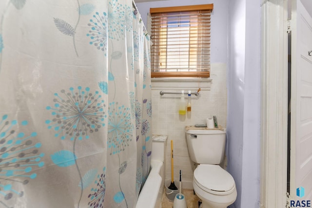 bathroom featuring shower / bath combo, toilet, and tile walls