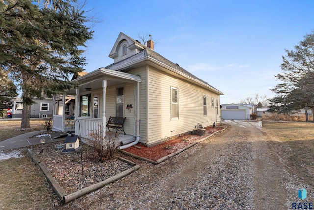 bungalow-style home featuring an outbuilding, covered porch, and a garage