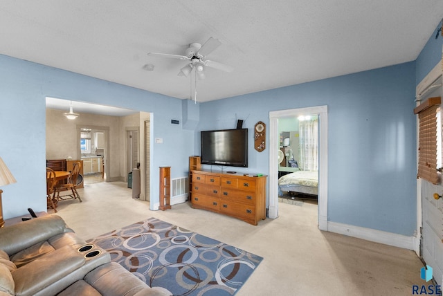 living room featuring light carpet, a textured ceiling, and ceiling fan