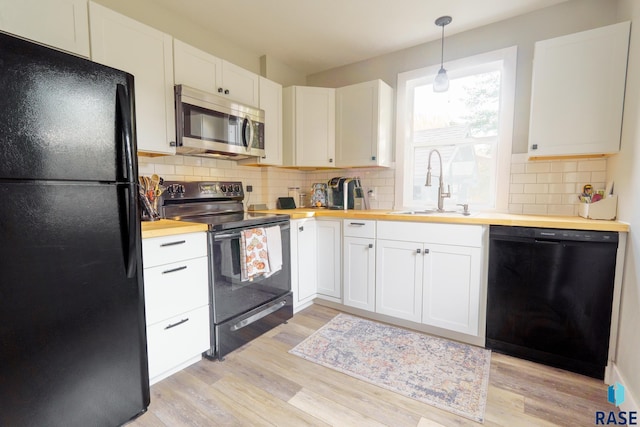 kitchen featuring black appliances, sink, white cabinets, and hanging light fixtures