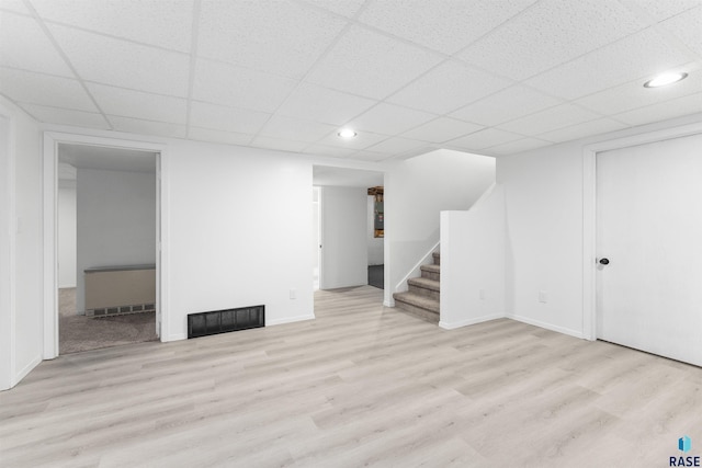 basement featuring light hardwood / wood-style flooring and a drop ceiling