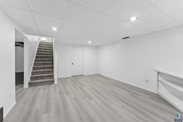 basement with a paneled ceiling and light wood-type flooring