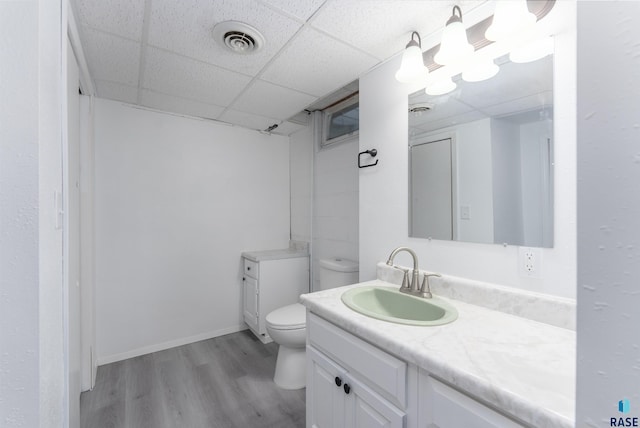 bathroom featuring a paneled ceiling, hardwood / wood-style floors, vanity, and toilet