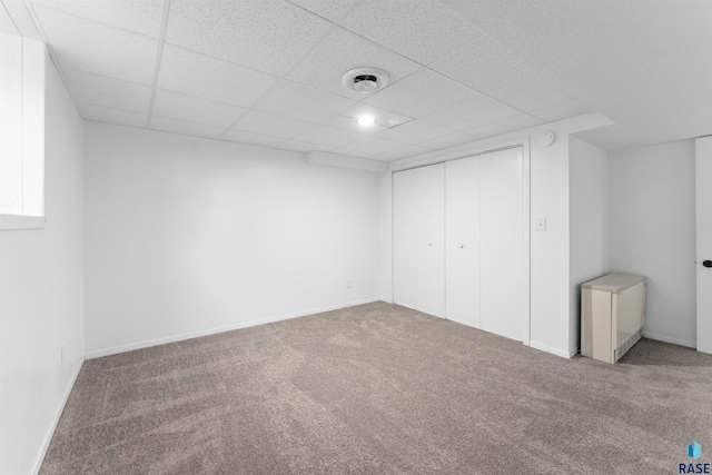 unfurnished bedroom with a paneled ceiling, carpet floors, and a closet