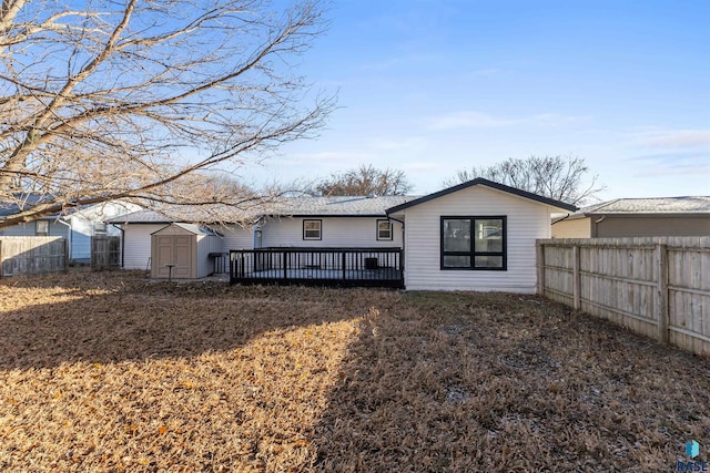 back of property with a deck, a storage shed, and a lawn