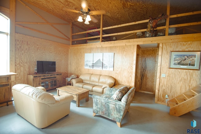 living room with concrete floors, high vaulted ceiling, ceiling fan, and wooden walls