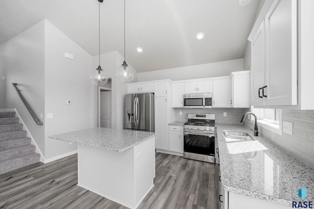 kitchen with pendant lighting, sink, appliances with stainless steel finishes, a kitchen island, and white cabinetry