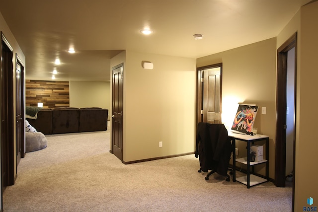 office with light carpet, an accent wall, wood walls, and baseboards