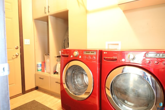 washroom with cabinets, light wood-type flooring, and washing machine and dryer