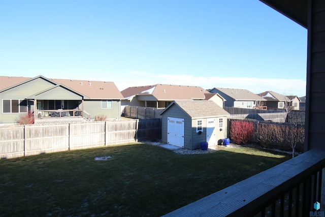 view of yard featuring a residential view, a fenced backyard, an outdoor structure, and a storage shed