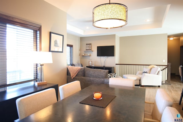 dining space featuring wood finished floors, a raised ceiling, and recessed lighting