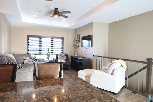 living room with dark wood-type flooring, a tray ceiling, ceiling fan, and recessed lighting