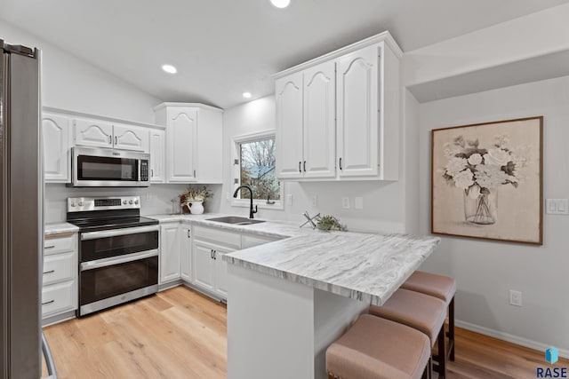 kitchen with white cabinets, light hardwood / wood-style floors, sink, and appliances with stainless steel finishes