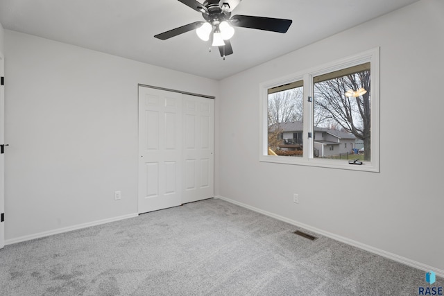 unfurnished bedroom with ceiling fan, light colored carpet, and a closet