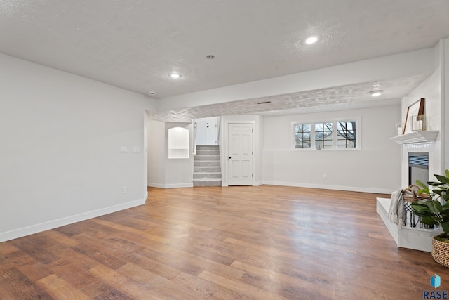 unfurnished living room with a fireplace, light hardwood / wood-style flooring, and a textured ceiling