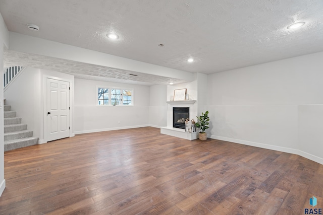 unfurnished living room with a fireplace, a textured ceiling, and hardwood / wood-style flooring