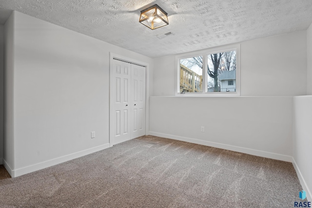 carpeted empty room featuring a textured ceiling