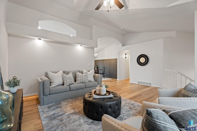 living room with ceiling fan, wood-type flooring, and vaulted ceiling