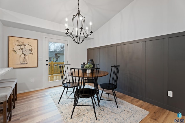 dining space featuring light hardwood / wood-style flooring, high vaulted ceiling, and an inviting chandelier