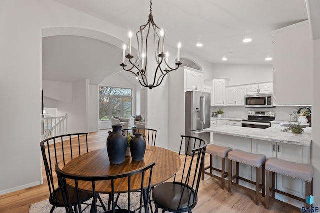 dining space with a notable chandelier, light wood-type flooring, sink, and vaulted ceiling