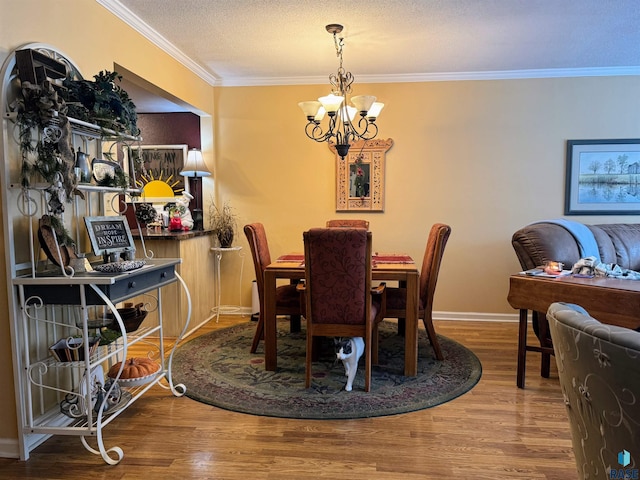 dining room featuring hardwood / wood-style flooring, ornamental molding, a textured ceiling, and a chandelier