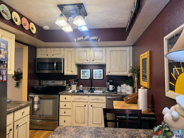 kitchen featuring stainless steel appliances, sink, a textured ceiling, and light wood-type flooring