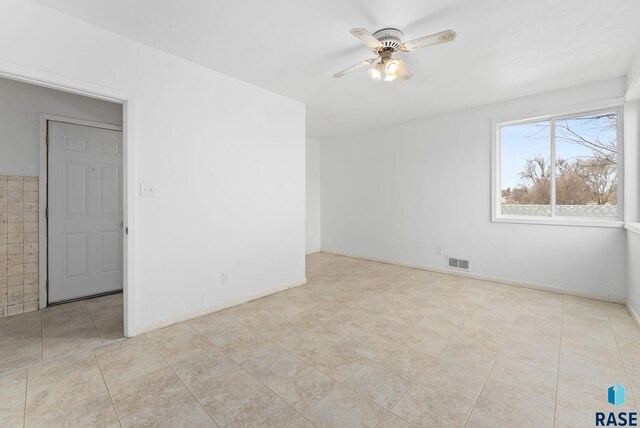 tiled empty room featuring ceiling fan