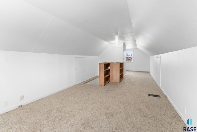 bonus room with light colored carpet and lofted ceiling