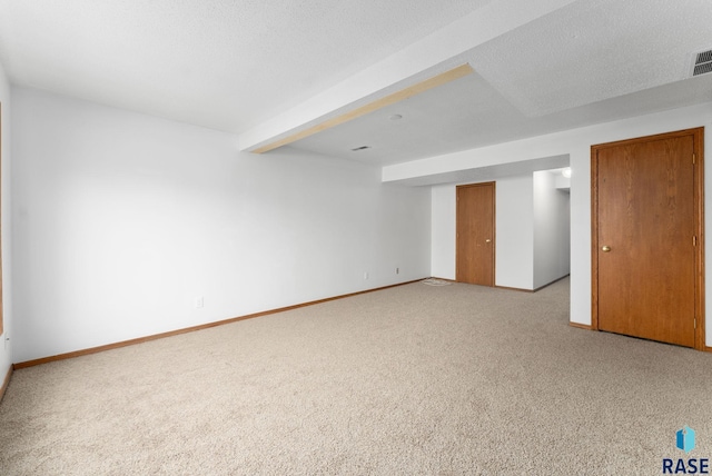 carpeted empty room with beamed ceiling and a textured ceiling