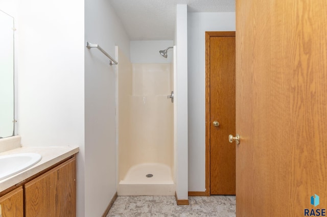 bathroom featuring a textured ceiling, vanity, and walk in shower