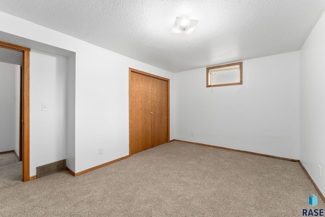 unfurnished bedroom with a textured ceiling, light colored carpet, and a closet