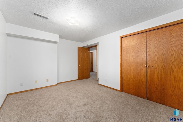 unfurnished bedroom featuring light carpet, a closet, and a textured ceiling