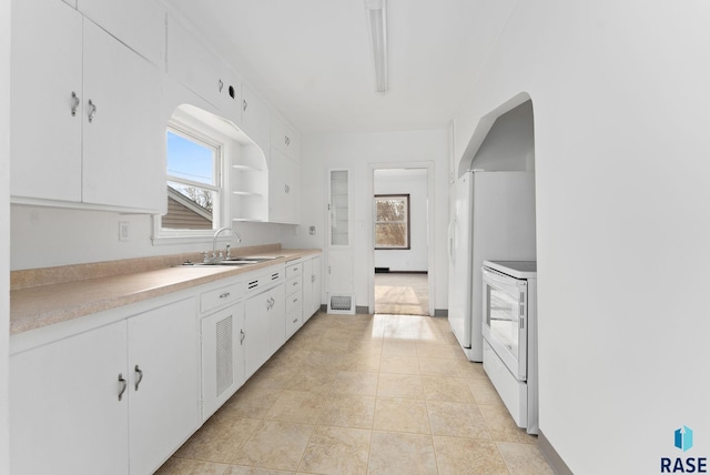 kitchen featuring white range oven, white cabinetry, sink, and light tile patterned floors