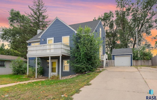 view of front of home with a yard, a balcony, an outdoor structure, and a garage