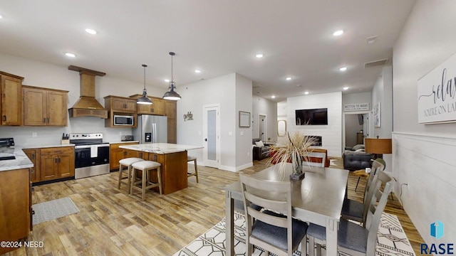 dining space with a brick fireplace and light hardwood / wood-style flooring