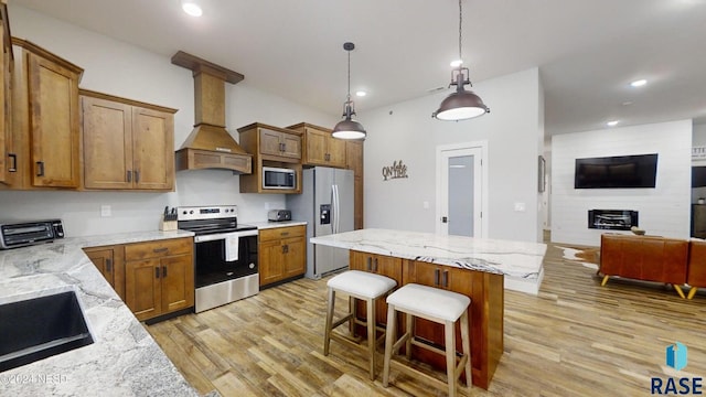 kitchen with light stone countertops, appliances with stainless steel finishes, premium range hood, and light hardwood / wood-style flooring