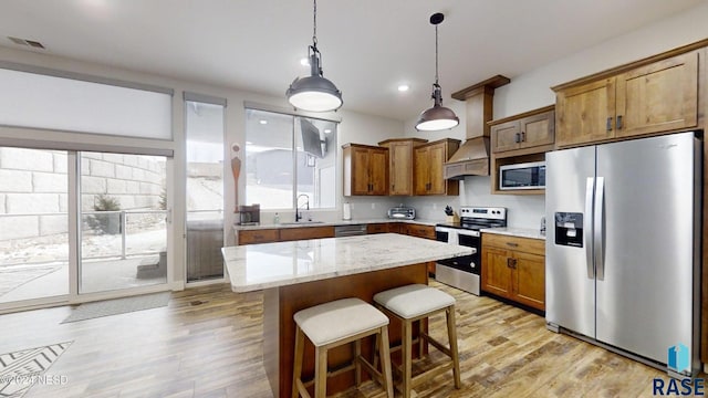 kitchen featuring light stone counters, a kitchen island, stainless steel appliances, and light hardwood / wood-style floors