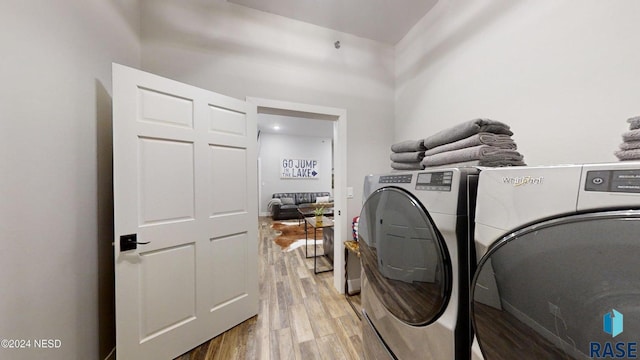 clothes washing area with independent washer and dryer and light wood-type flooring