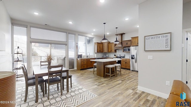 kitchen featuring a kitchen breakfast bar, sink, hanging light fixtures, a kitchen island, and stainless steel appliances