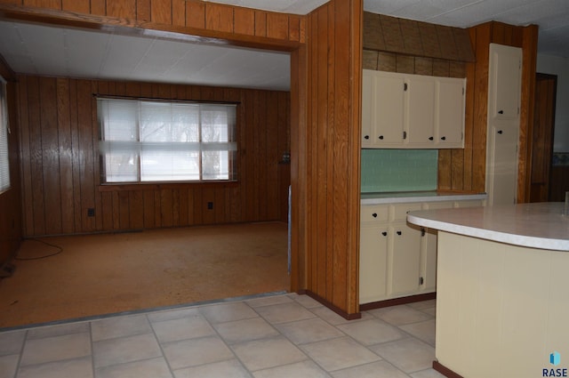 kitchen featuring wood walls, light colored carpet, and backsplash