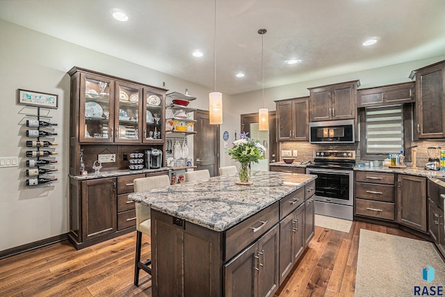 kitchen featuring appliances with stainless steel finishes, dark hardwood / wood-style flooring, dark brown cabinetry, and pendant lighting